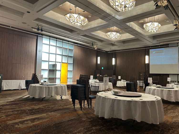 披露宴会場の写真です。天井が高く、広々としています。茶系でまとめられており、温かみを感じます。