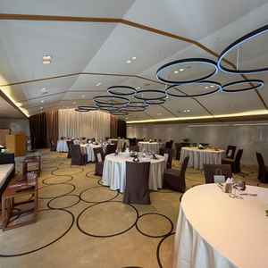 落ち着いた色味で統一された上品な披露宴会場で、天井の円形照明が印象的。