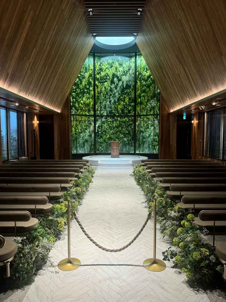 挙式会場。木のぬくもりと緑のコントラストが美しく、柔らかな光に包まれた空間で神聖さを感じました。