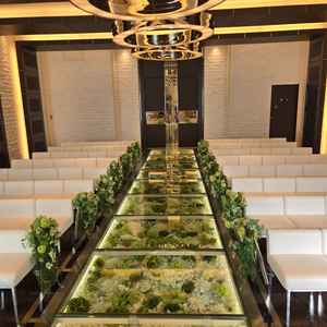 ガラス張りのバージンロードの下に敷き詰められた白と緑の花々が、清楚で素敵な雰囲気を演出していました。