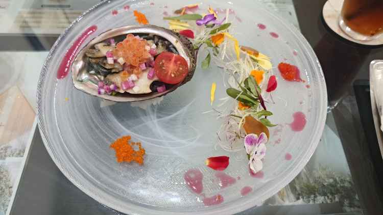 アワビを使ったひと皿。周りには野菜やエディブルフラワーが散りばめられている。