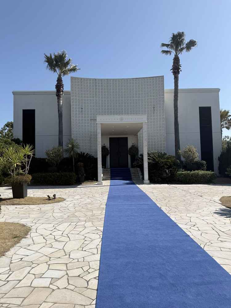 青空とヤシの木が映える、非日常感あふれる結婚式場の入口です。