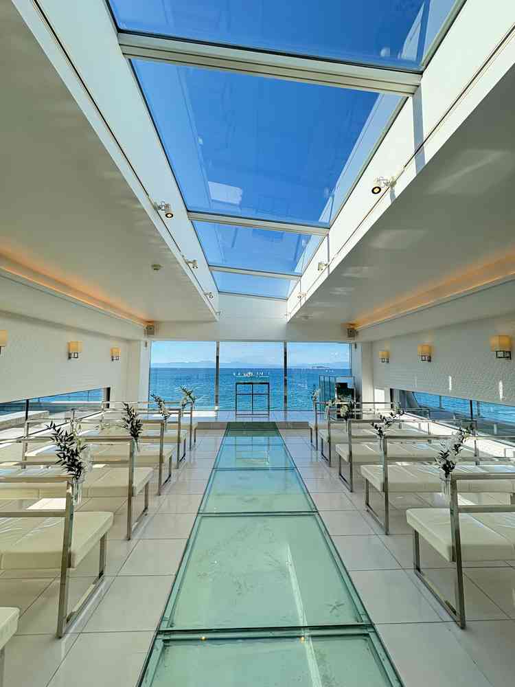 自然光が最大限に入るチャペル。バージンロードがガラス面の下に砂浜と貝殻が散りばめられている。