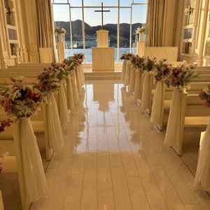白基調のチャペルの写真。全体と参列者席も白基調になっており、装花でバージンロードが華やかでした。