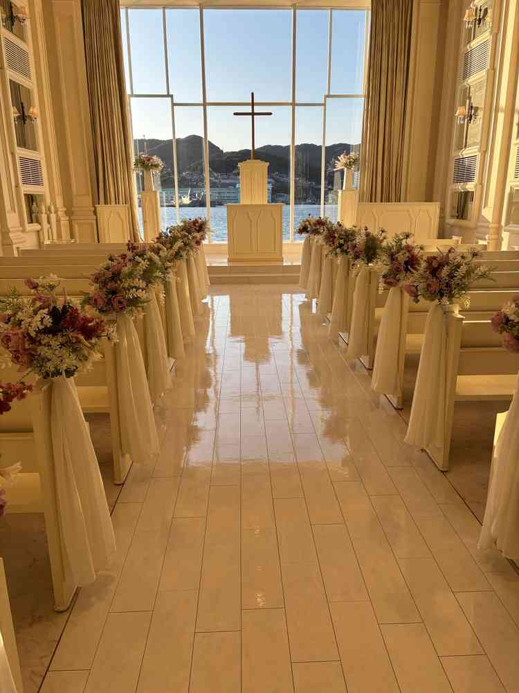 白基調のチャペルの写真。全体と参列者席も白基調になっており、装花でバージンロードが華やかでした。