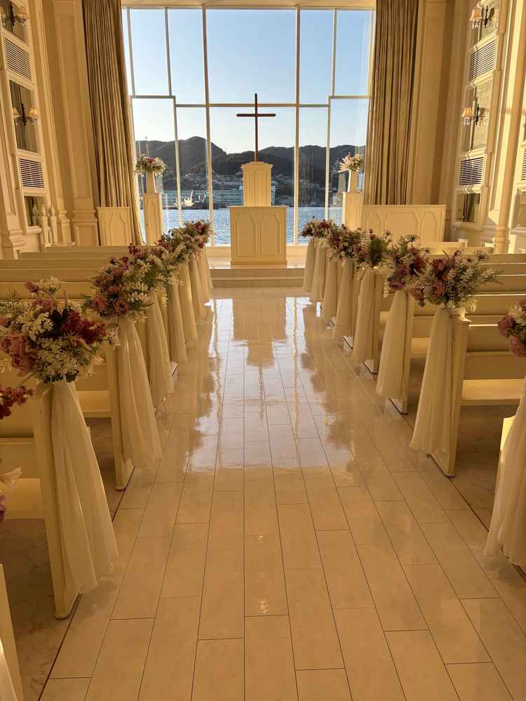 白基調のチャペルの写真。全体と参列者席も白基調になっており、装花でバージンロードが華やかでした。