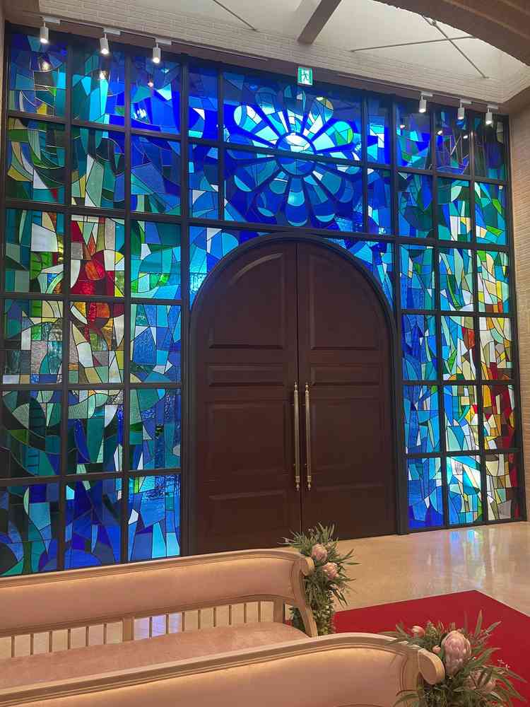 挙式会場。新郎新婦が入場する大事な場面において、ステンドグラスが背景になることで、感動的な演出に。