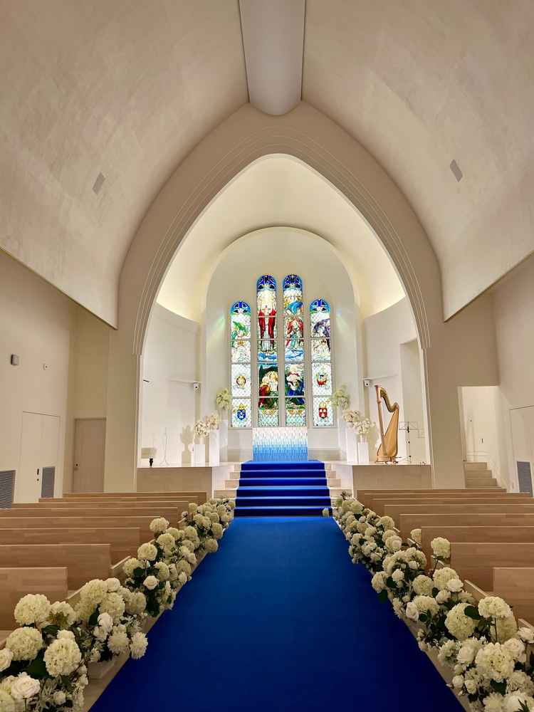 青いバージンロードが印象的でステンドグラスは唯一無二の印象。天井が高く、ムービーを流すのにも映える。