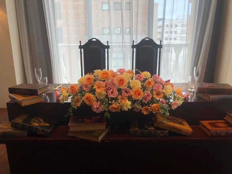 本棚が魅力的な披露宴会場のメインテーブルです。テーブルの上に本と花があり、暖かさを感じました。