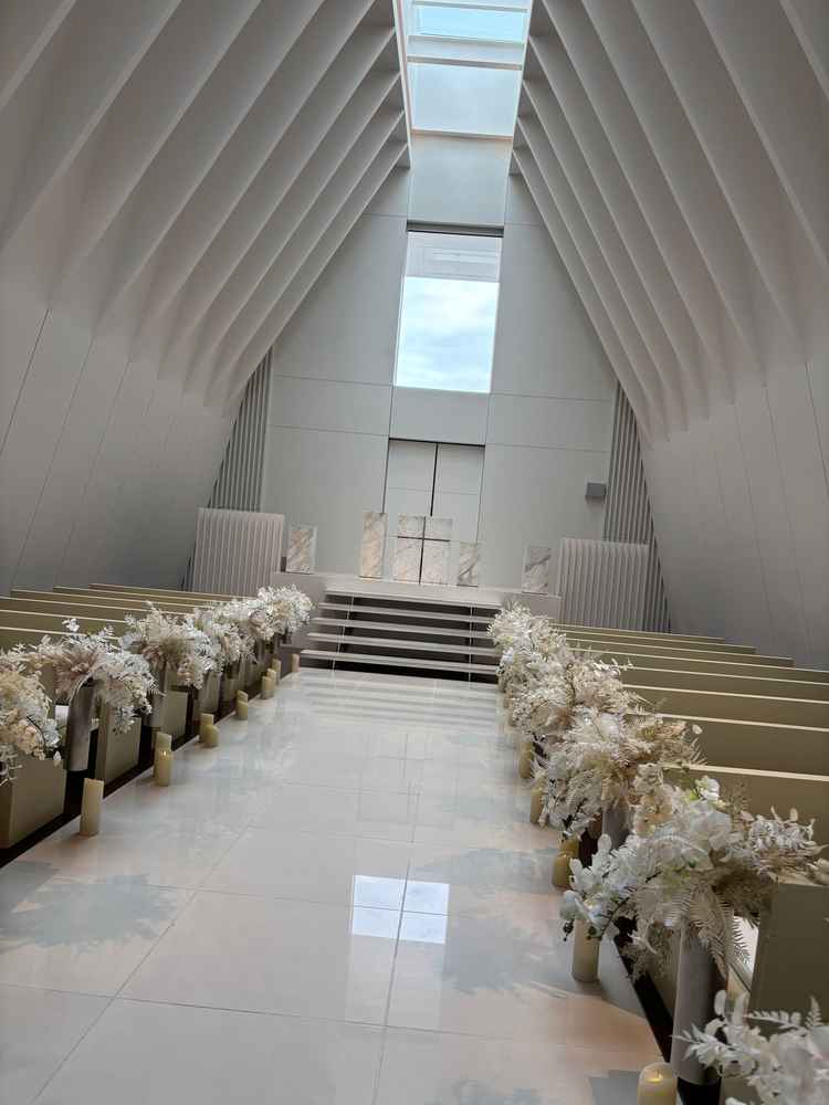 白基調のチャペル全体の写真。白色の装花でより綺麗に見えるバージンロードでした。