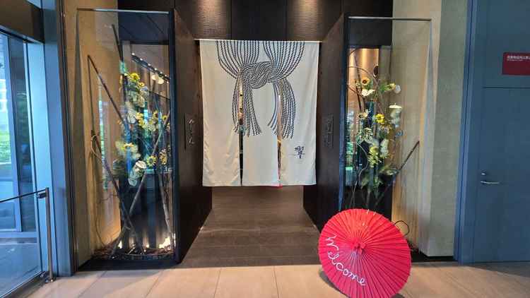 和の趣を感じさせる番傘と、華やかなフラワーアレンジメントが飾られた上品なエントランスです。