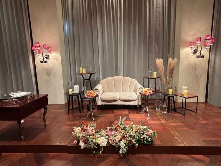 披露宴会場「ルビーノ」の高砂。木目の会場の雰囲気とソファ席とお花がマッチしていた。