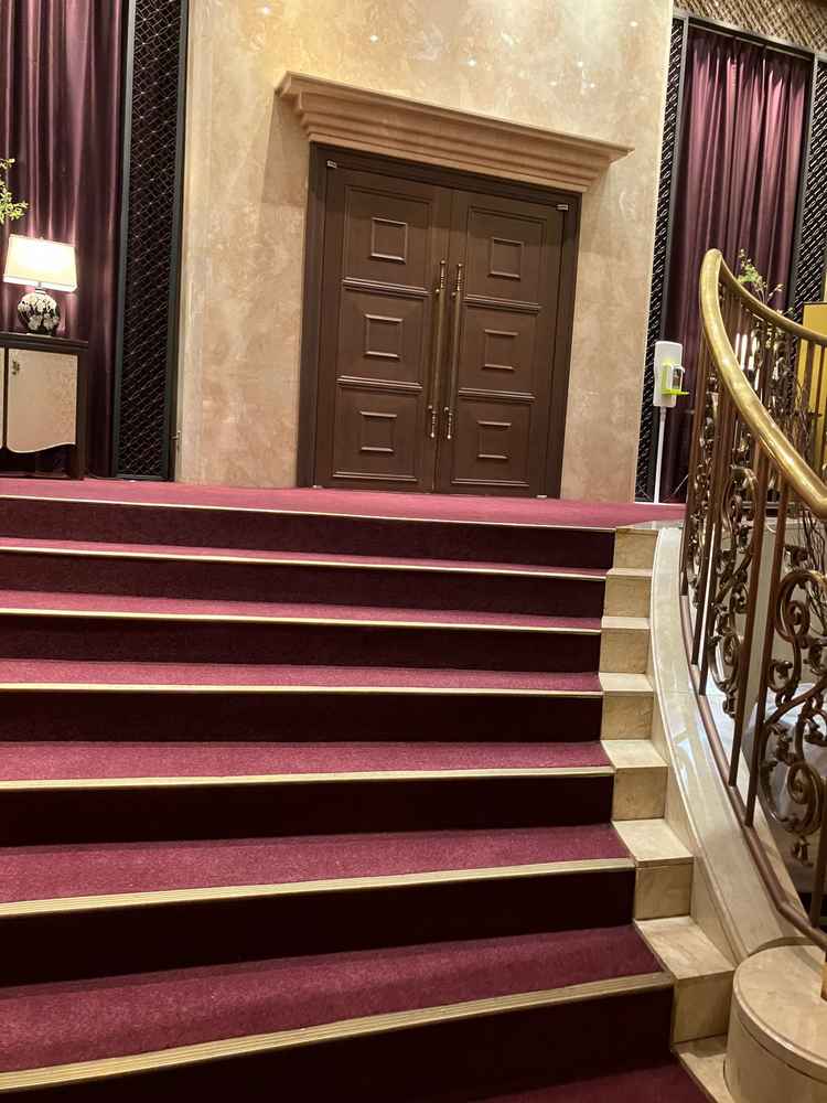 披露宴会場の入り口。アーチを描く階段と、建具の装飾やカーペットの色合いが重厚感もありドレスが映えそう