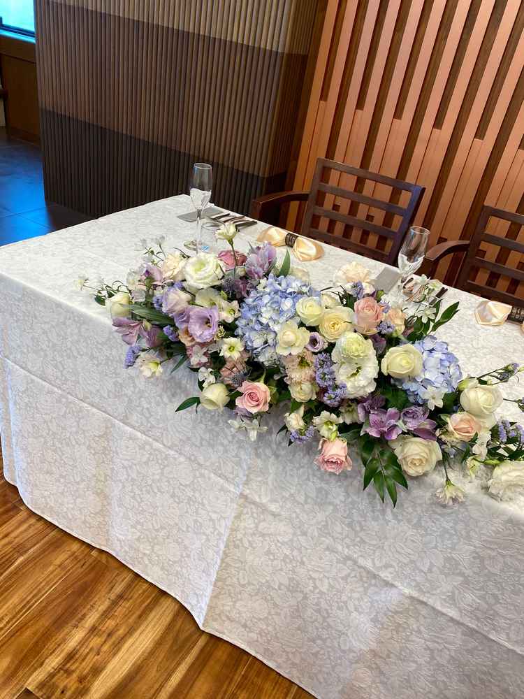 淡い色でコーディネートされた披露宴会場の花。落ち着いた雰囲気でテーブルクロスとの相性◎