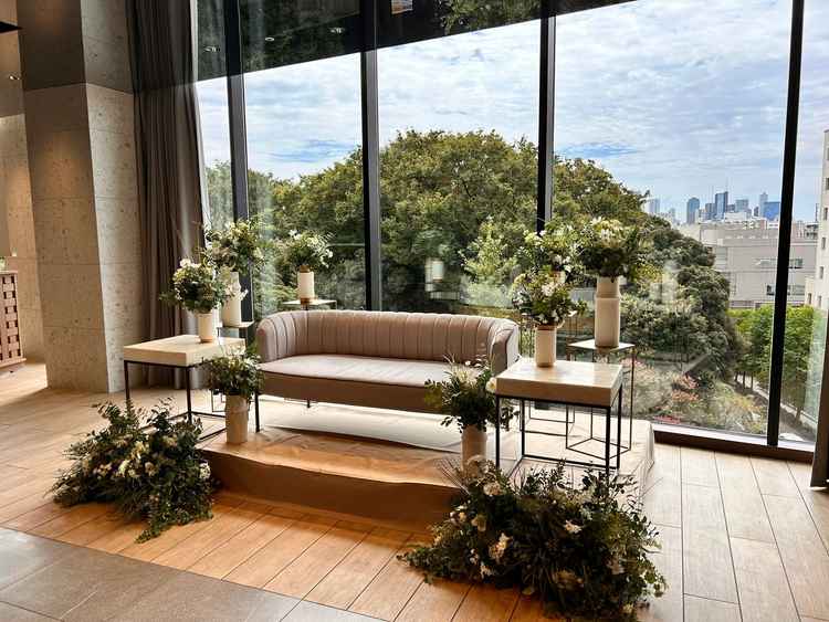 【披露宴会場の新郎新婦席背景】大学の緑が映り自然を感じる。ただ角度を変えるとJREASTホテルあり。