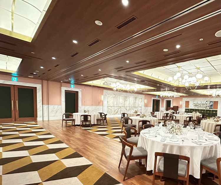 木目調の天井と幾何学模様の床が印象的な上品な披露宴会場だと思いました。