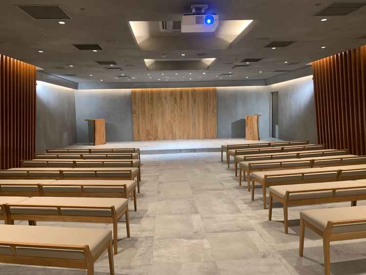 披露宴会場。木目調の落ち着いたデザインかつ誓いの場と客席の高低差が少なくアットホームな雰囲気。