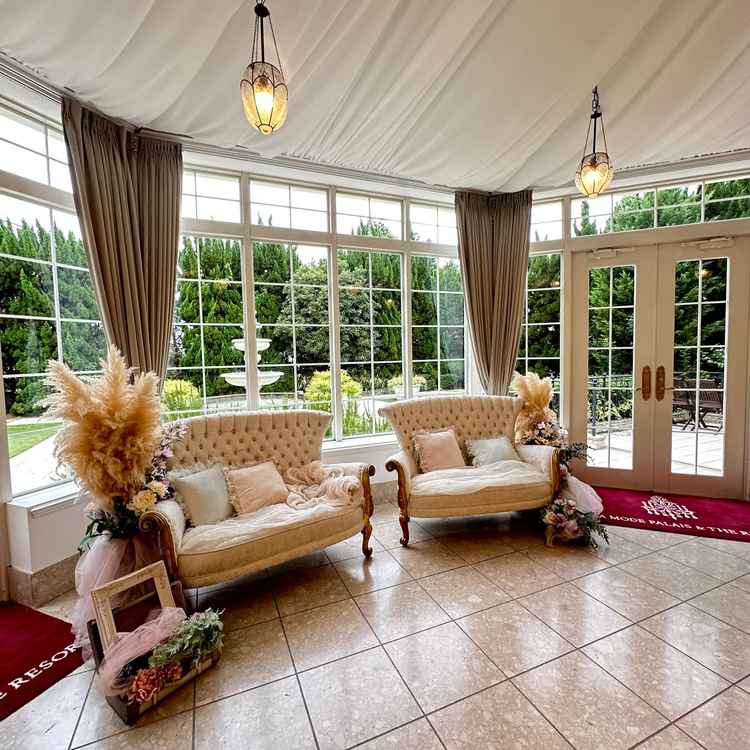 白基調の披露宴会場の後方にあるソファと、併設のガーデンの様子。フォトブースにも使えそう。