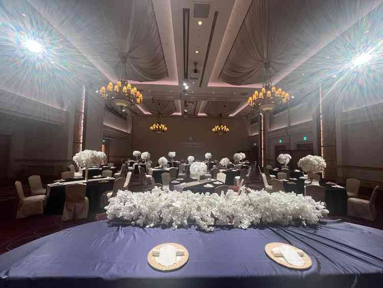 別の披露宴会場はホテルのイメージ通りの空間で重厚感もありつつ白い花が映える。スクリーンも使える。