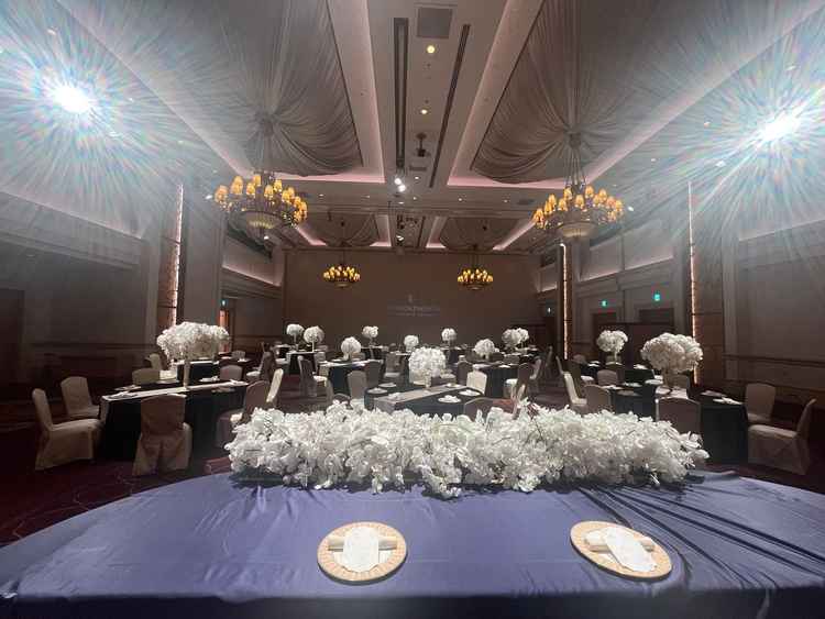 別の披露宴会場はホテルのイメージ通りの空間で重厚感もありつつ白い花が映える。スクリーンも使える。