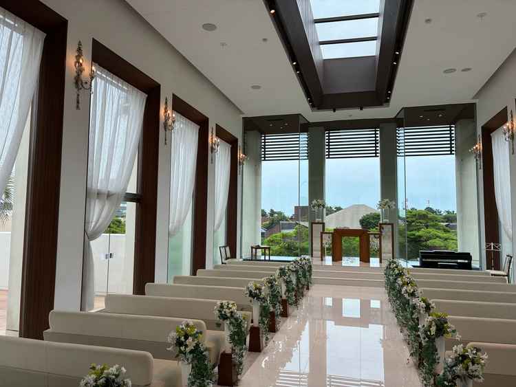 自然光で明るい結婚式場。白を基調としたバージンロードは、天井からの光で祭壇が反射している。