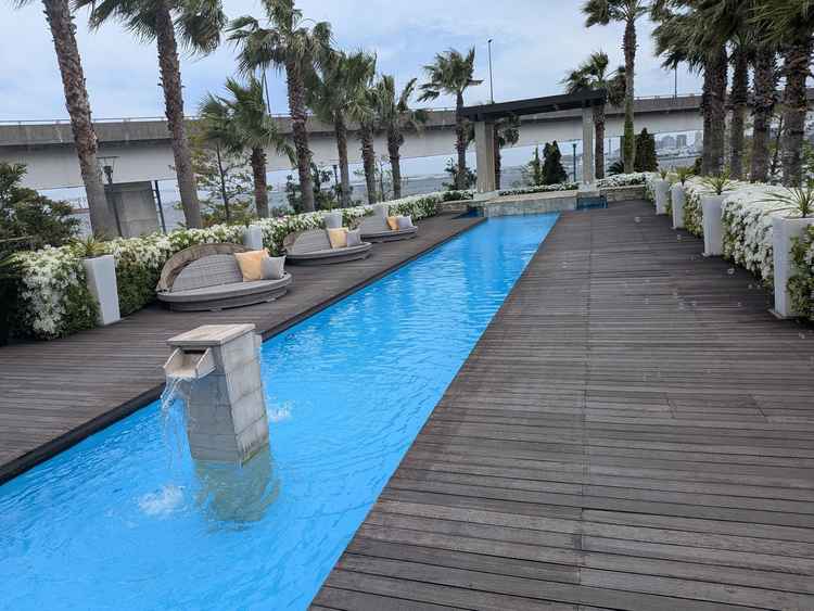 ガーデンテラス。ヤシの木とプールが印象的で、奥には海が広がっています。