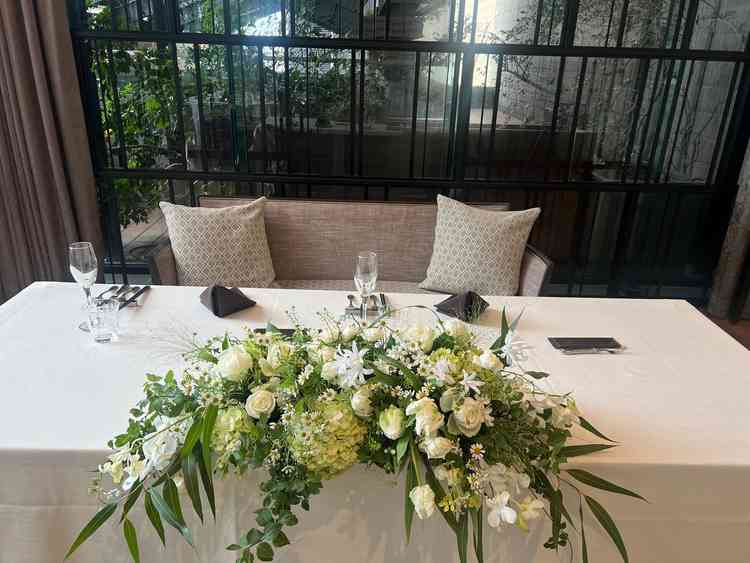 披露宴会場の高砂。テーブルスタイルで、テーブル周りの花は自分好みにカスタマイズ可能。