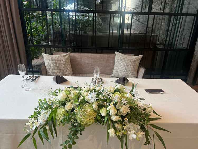 披露宴会場の高砂。テーブルスタイルで、テーブル周りの花は自分好みにカスタマイズ可能。