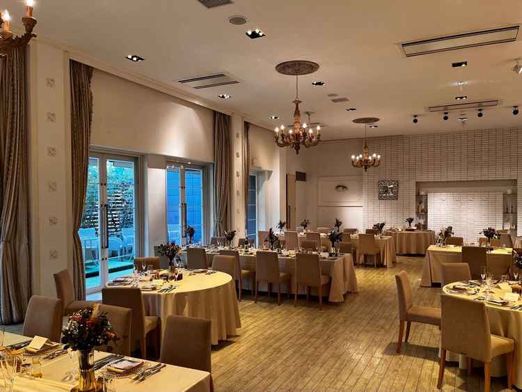 白を基調とする披露宴会場の全体の写真。シャンデリアがウッド調で魅力的だった。