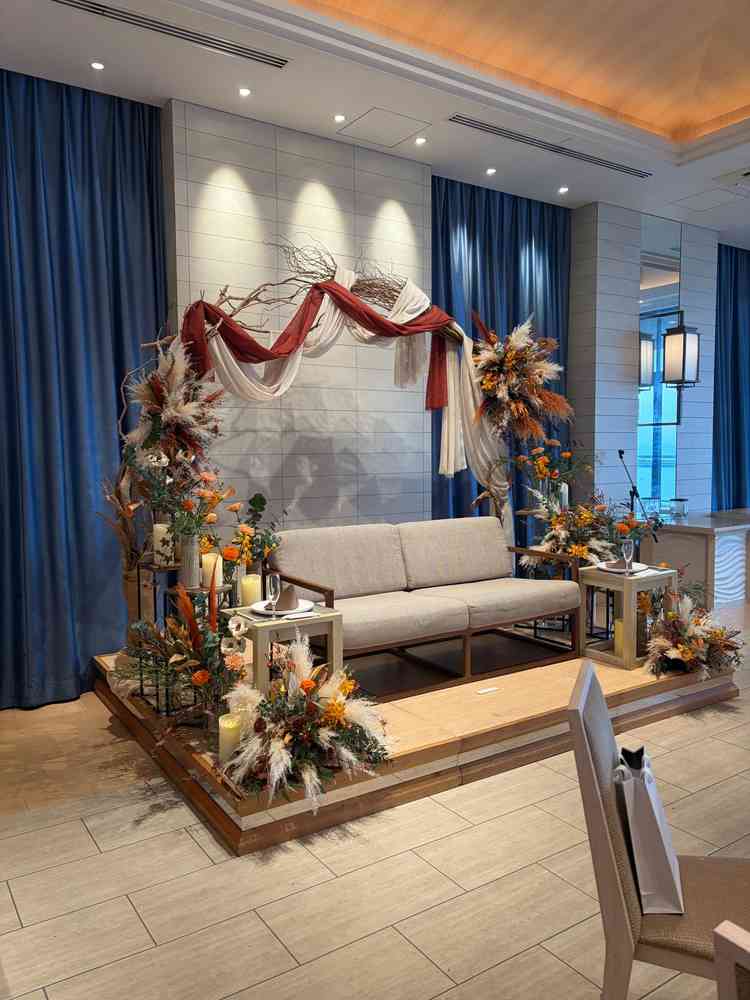 披露宴会場の素敵な高砂の写真。オレンジ基調の生花とアーチが素敵でした。