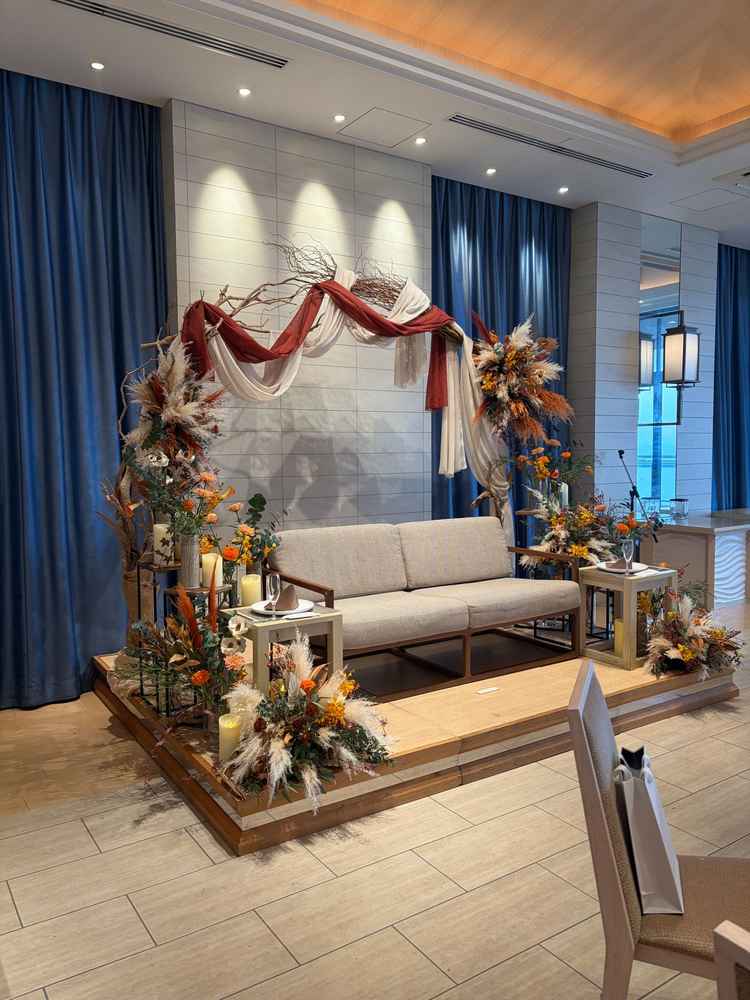 披露宴会場の素敵な高砂の写真。オレンジ基調の生花とアーチが素敵でした。