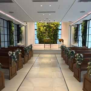 キリスト教式の挙式場で木目調の座るイス、後ろが植物のグリーン基調であり自然を感じられます。