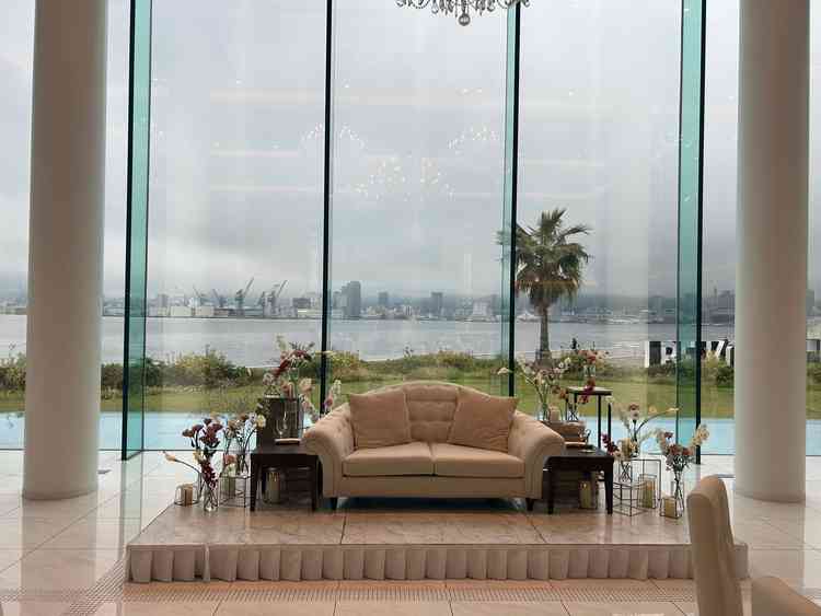 披露宴会場で新郎新婦が腰掛けるソファ。背後には海と神戸の街並みが見え、写真映えする。