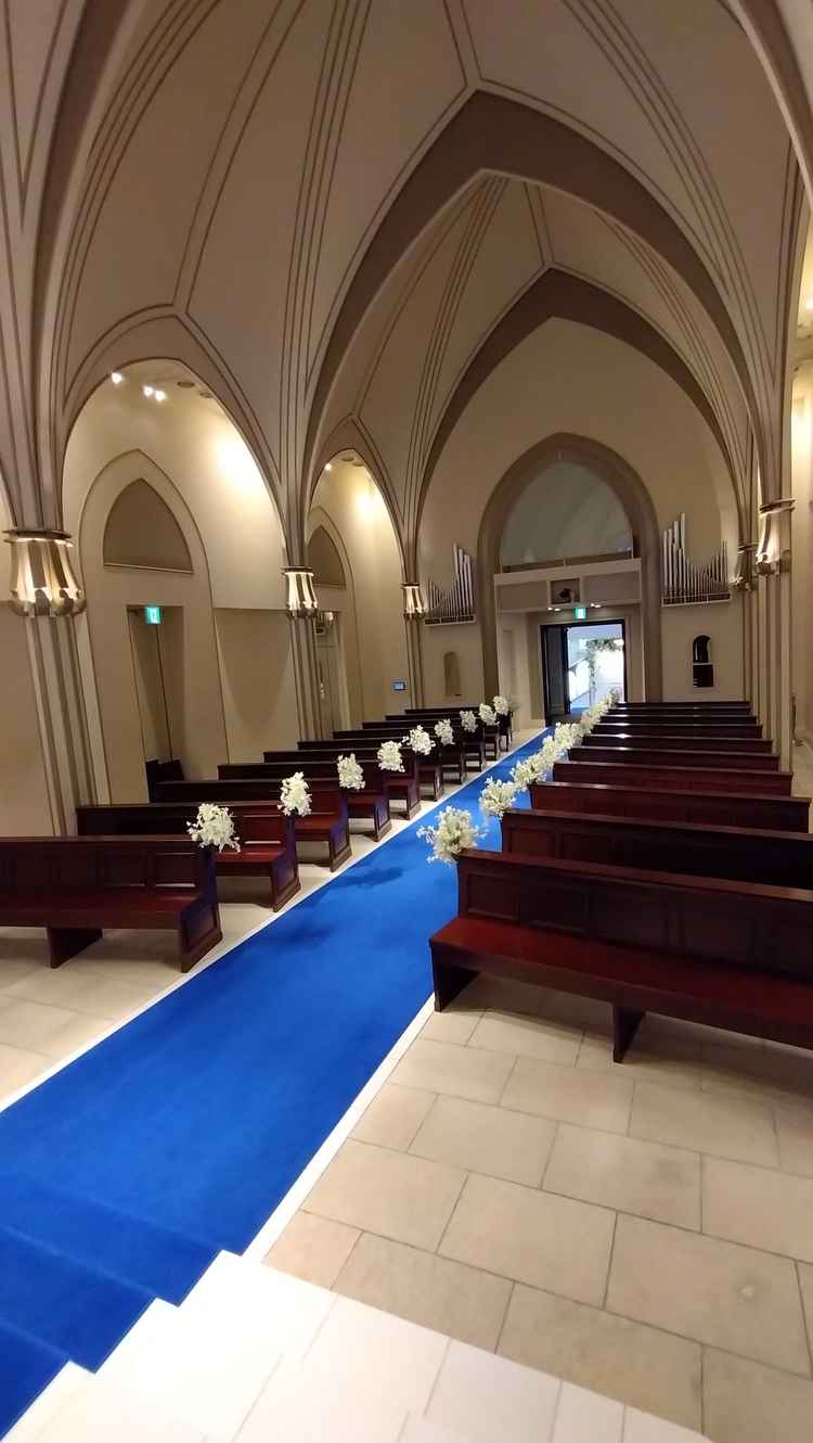 青のバージンロードは、実際に見ると青すぎず落ち着いていてよい印象。チャペルの天井も高い。