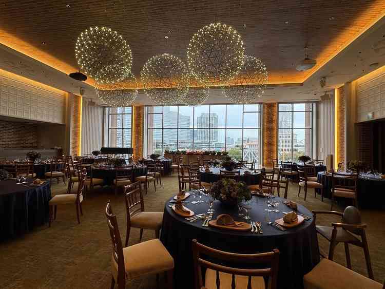 新郎新婦の背景にはみなとみらいが一望できるガラス窓。広々とした披露宴会場に、デザイン性のあるライト。