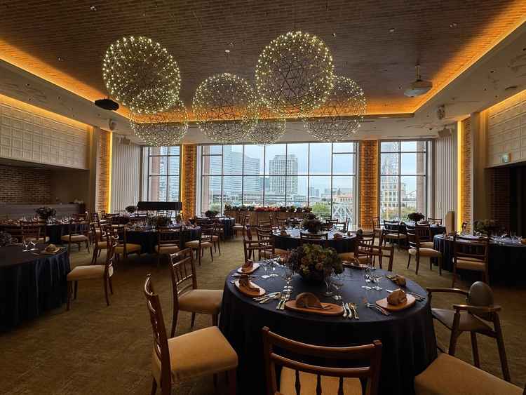 新郎新婦の背景にはみなとみらいが一望できるガラス窓。広々とした披露宴会場に、デザイン性のあるライト。