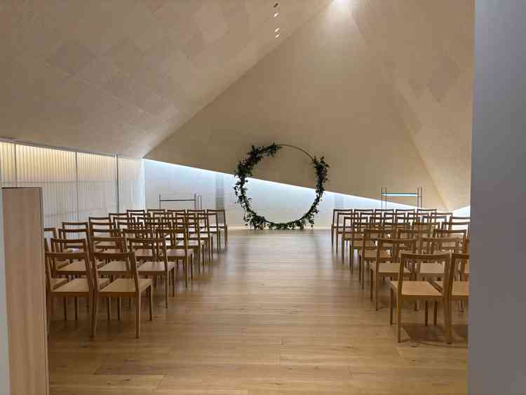 和紙が使われていて三角形が特徴のチャペル。木の椅子は温かみがある。
