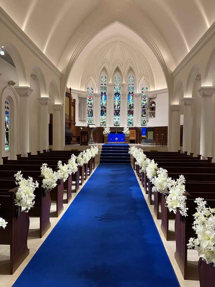 ブルーのバージンロードと大聖堂型のチャペル。天井も高く広々としており、ドレス姿映えのする空間。
