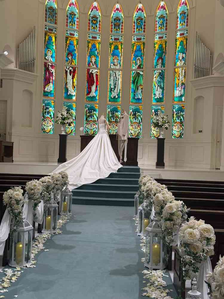 青いバージンロードに白い花達が飾られ爽やか。そこに鮮やかなステンドグラスがよく映えるチャペルでした。