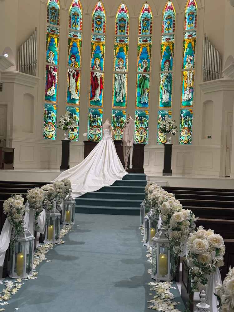 青いバージンロードに白い花達が飾られ爽やか。そこに鮮やかなステンドグラスがよく映えるチャペルでした。