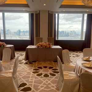 披露宴会場(小)の新郎新婦の席の写真。披露宴会場の窓も広く、写真撮影の背景が映える。