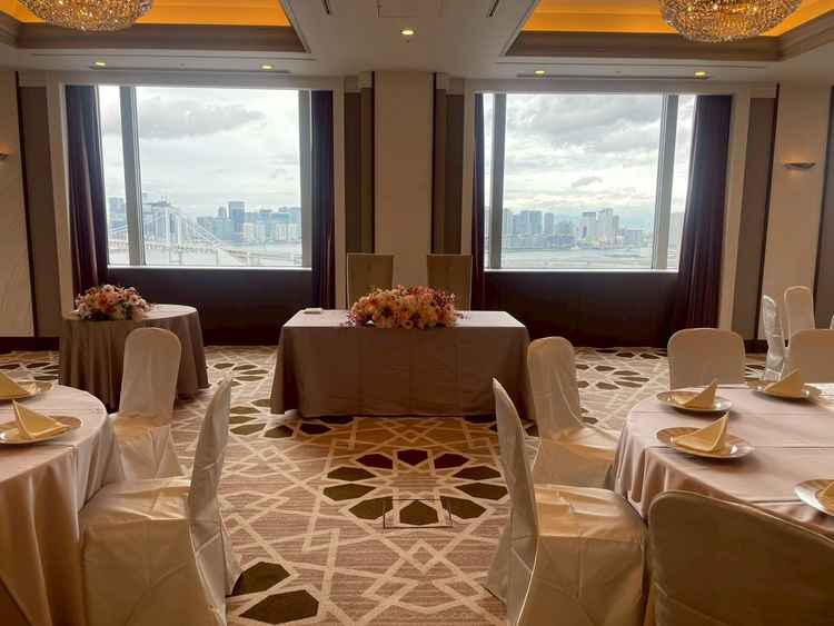 披露宴会場(小)の新郎新婦の席の写真。披露宴会場の窓も広く、写真撮影の背景が映える。