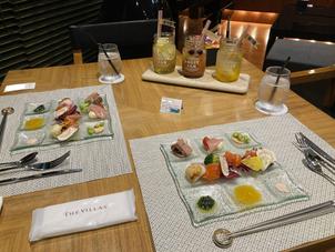 コース料理の最初の前菜9種のパレット盛りと、奥のドリンクは待機スペースのバーカウンターの物です。