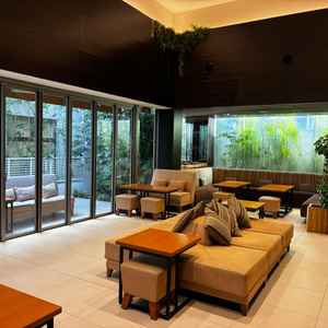 待合スペース。横長のソファが並べられており、くつろぎやすそう。窓も全開できるので広々と使える。