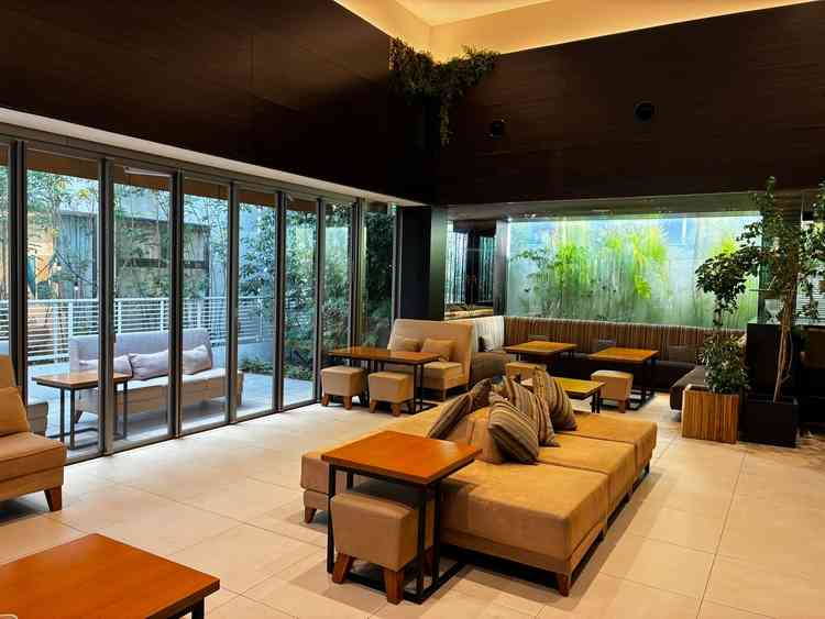 待合スペース。横長のソファが並べられており、くつろぎやすそう。窓も全開できるので広々と使える。