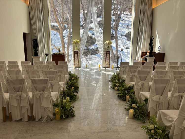 白を基調とした挙式会場の写真。窓からはお日様と木々が見えます。