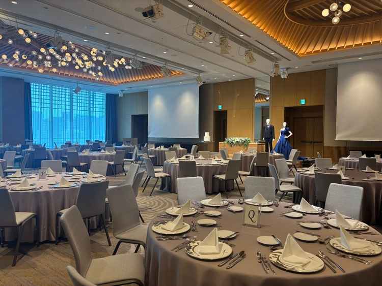 披露宴会場の円卓セッティング。大きなシャンデリアが華やかで、ゲスト同士の距離も近く温かい雰囲気の空間