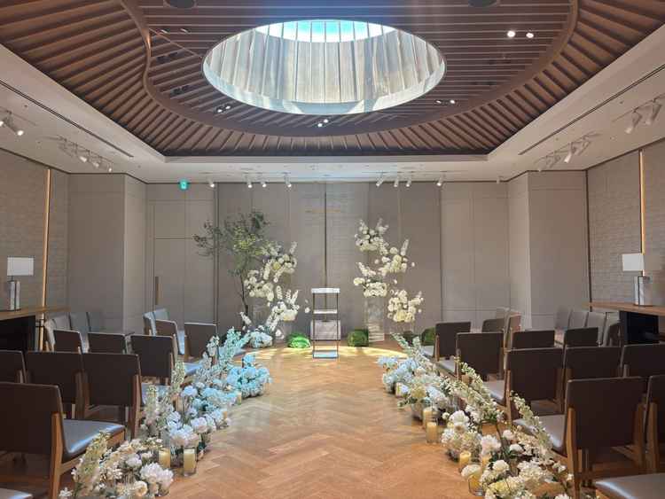 チャペル全景。天井の円形照明が印象的で、バージンロード沿いの装花も美しく、明るく厳かな雰囲気の挙式会