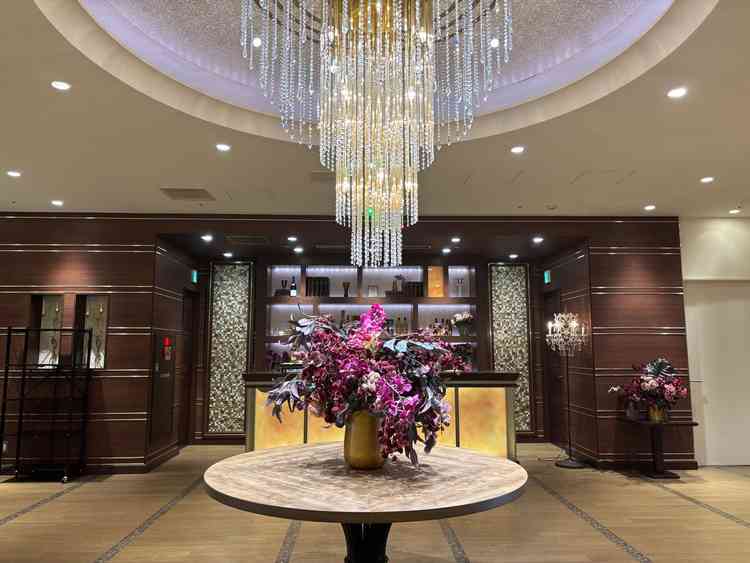 披露宴会場。エレベーター降りてからの景色。シャンデリアや大きなお花が置いてあり豪華さを感じた。