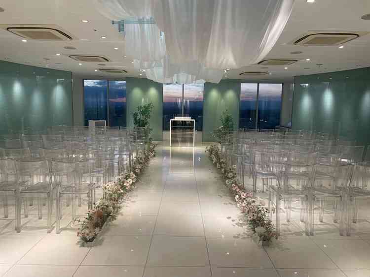 透明感のあるチャペル。夜景が綺麗に見え、ドレスが映えそう。バージンロードの花も落ち着いた色味で良い。